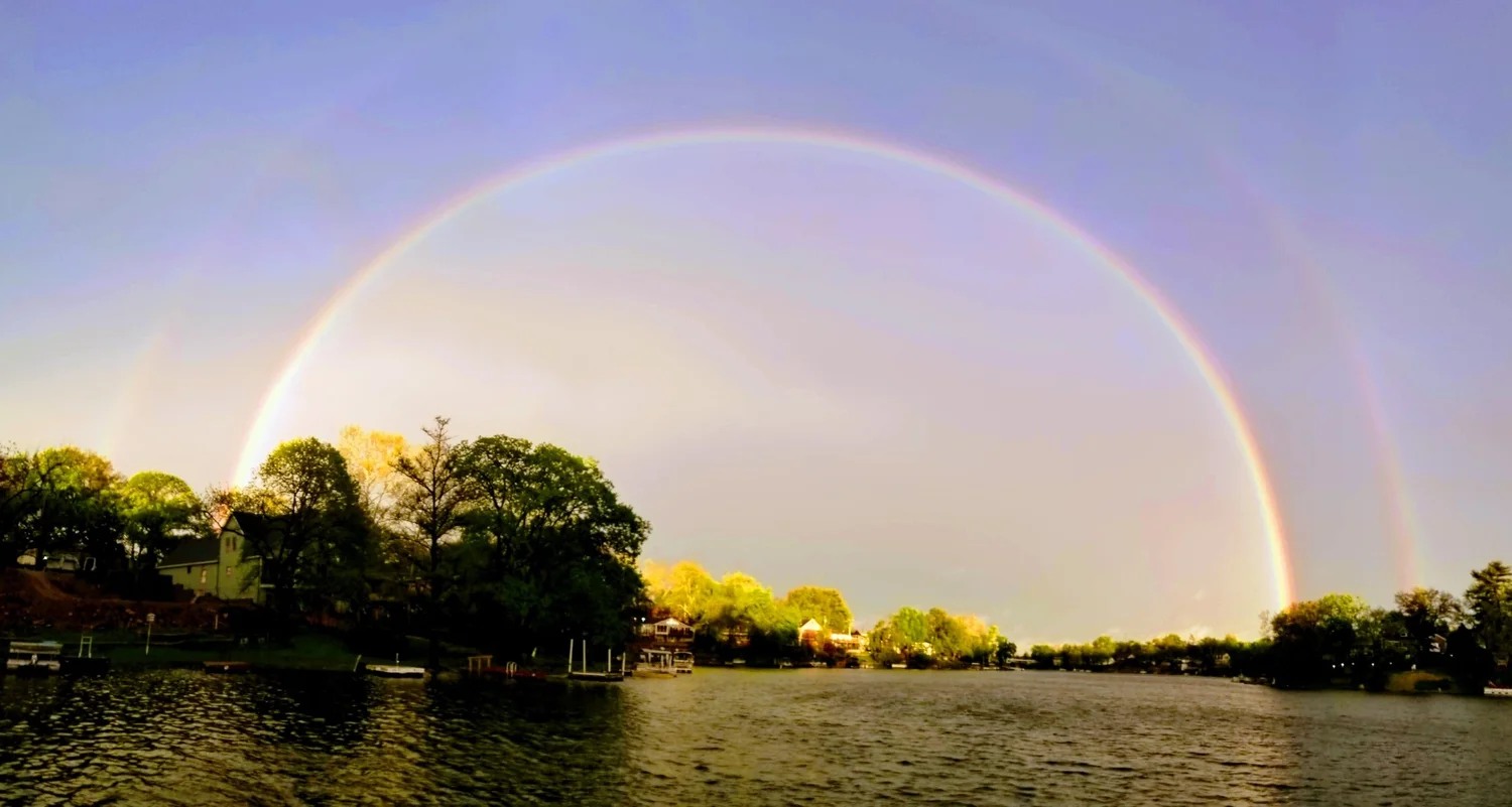 Rainbow stretching across Lake Waukomis above shoreline homes